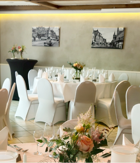 Eingerichteter Saal für eine Veranstaltung. Schön gedeckte Tische mit Blumensträußen in einer hellen und freundlichen Atmosphäre